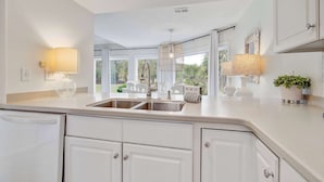 A modern kitchen with white cabinetry, a double sink, and pendant lighting.