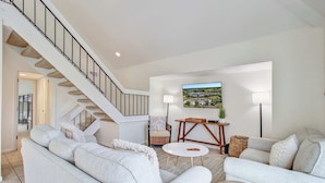 A spacious living room with a staircase, a large window with a view, and a cozy seating area.