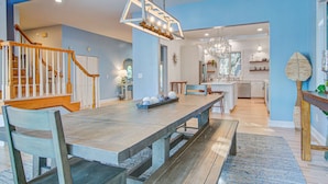A spacious dining area with a long wooden table, benches, and a chandelier.