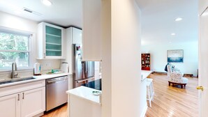 Una cucina moderna con mobili bianchi, elettrodomestici in acciaio inossidabile e un'ampia finestra.