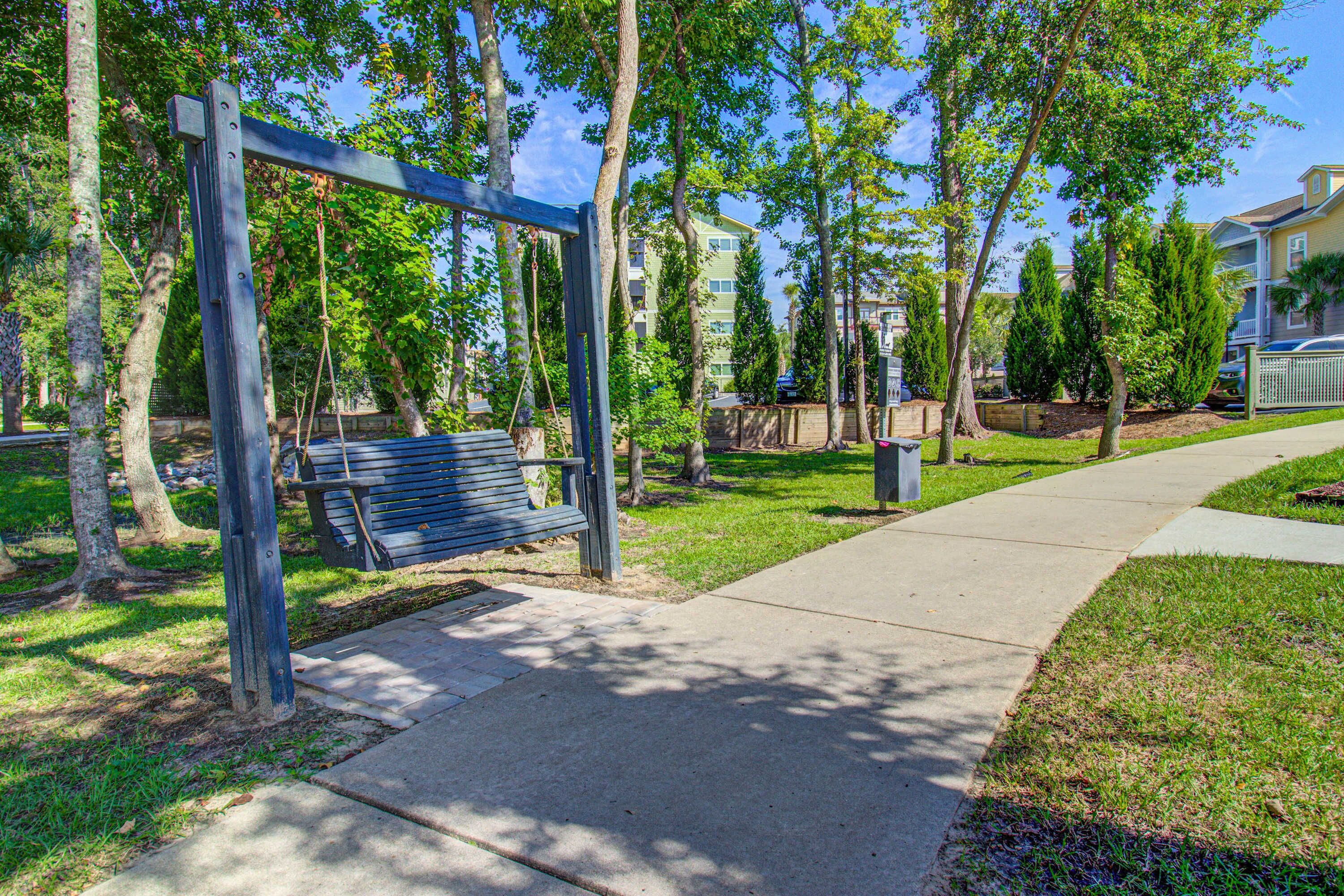 A park with a wooden swing set and a bench.