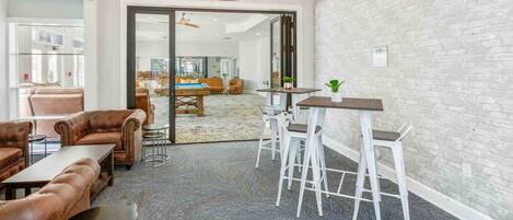 Uma área de estar moderna com sofás de couro, uma mesa de centro e um bar com banquetas.