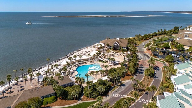 Een resort met een zwembad, strand en een boot op het water.