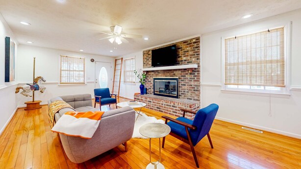 A living room with a fireplace, a television, and a ceiling fan. - Park Circle home close to restaurants w/ AC & private W/D (North Charleston)