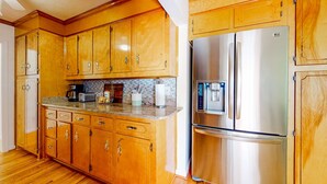 A kitchen with wooden cabinets, a stainless steel refrigerator, and a granite countertop. - Park Circle home close to restaurants w/ AC & private W/D (North Charleston)