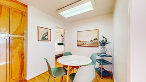 A dining area with a round table, chairs, a ceiling light, wooden cabinets, and artwork on the walls. - Park Circle home close to restaurants w/ AC & private W/D (North Charleston)