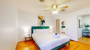 A hotel room with a bed, a ceiling fan, a nightstand, and a door leading to another room. - Park Circle home close to restaurants w/ AC & private W/D (North Charleston)