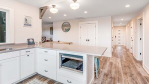 A modern kitchen with white cabinetry, a built-in oven, and a countertop with a sink. - Fantastic coastal retreat with private dock, gas grill, two decks, & fast WiFi (Folly Beach)