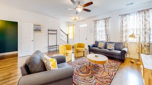 A modern living room with a grey sofa, yellow armchairs, a grey couch, and a colorful rug. - Snowbird-friendly townhouse with pool, tennis court, & central AC (North Charleston)