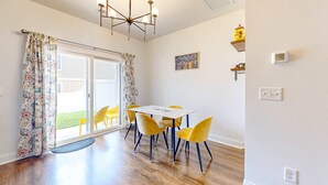A dining area with a table and chairs, a chandelier, and a sliding glass door leading to a patio. - Snowbird-friendly townhouse with pool, tennis court, & central AC (North Charleston)