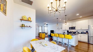 A modern kitchen with white cabinets, stainless steel appliances, and yellow bar stools. - Snowbird-friendly townhouse with pool, tennis court, & central AC (North Charleston)