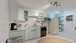 Una cocina moderna con armarios blancos, microondas, lavavajillas y cafetera.