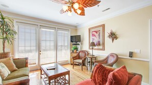 Un salon avec un canapé rouge, une table basse en bois, un téléviseur et un ventilateur de plafond.
