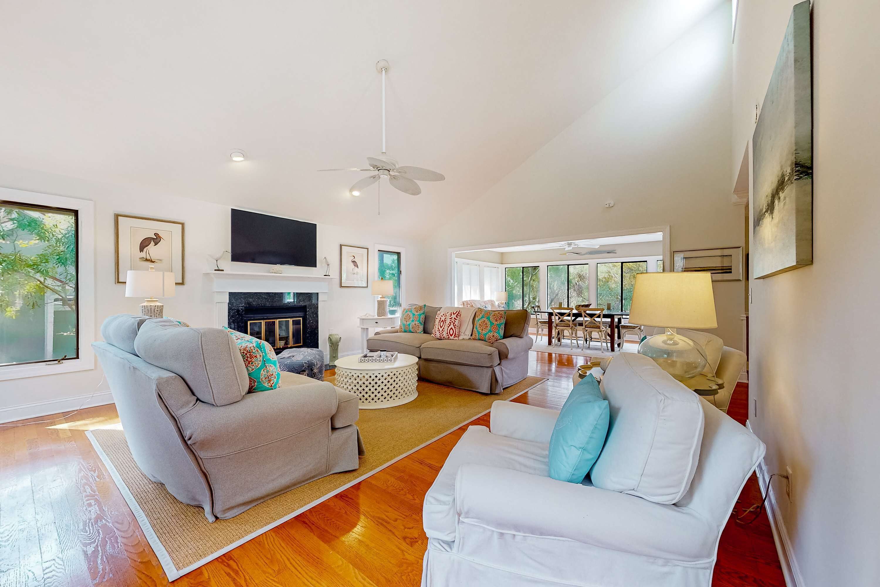 A spacious living room with a fireplace, two sofas, a coffee table, and a TV mounted on the wall.