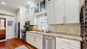 A modern kitchen with white cabinets, stainless steel appliances, and a granite countertop. - North Central, 30-Day Rental Home w/Double Porches, Garden Patio, and Free WiFi (Charleston)