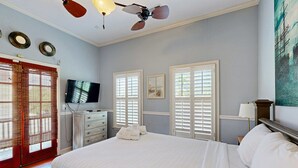 A bedroom with a bed, a ceiling fan, a television, and a window with blinds. - North Central, 30-Day Rental Home w/Double Porches, Garden Patio, and Free WiFi (Charleston)