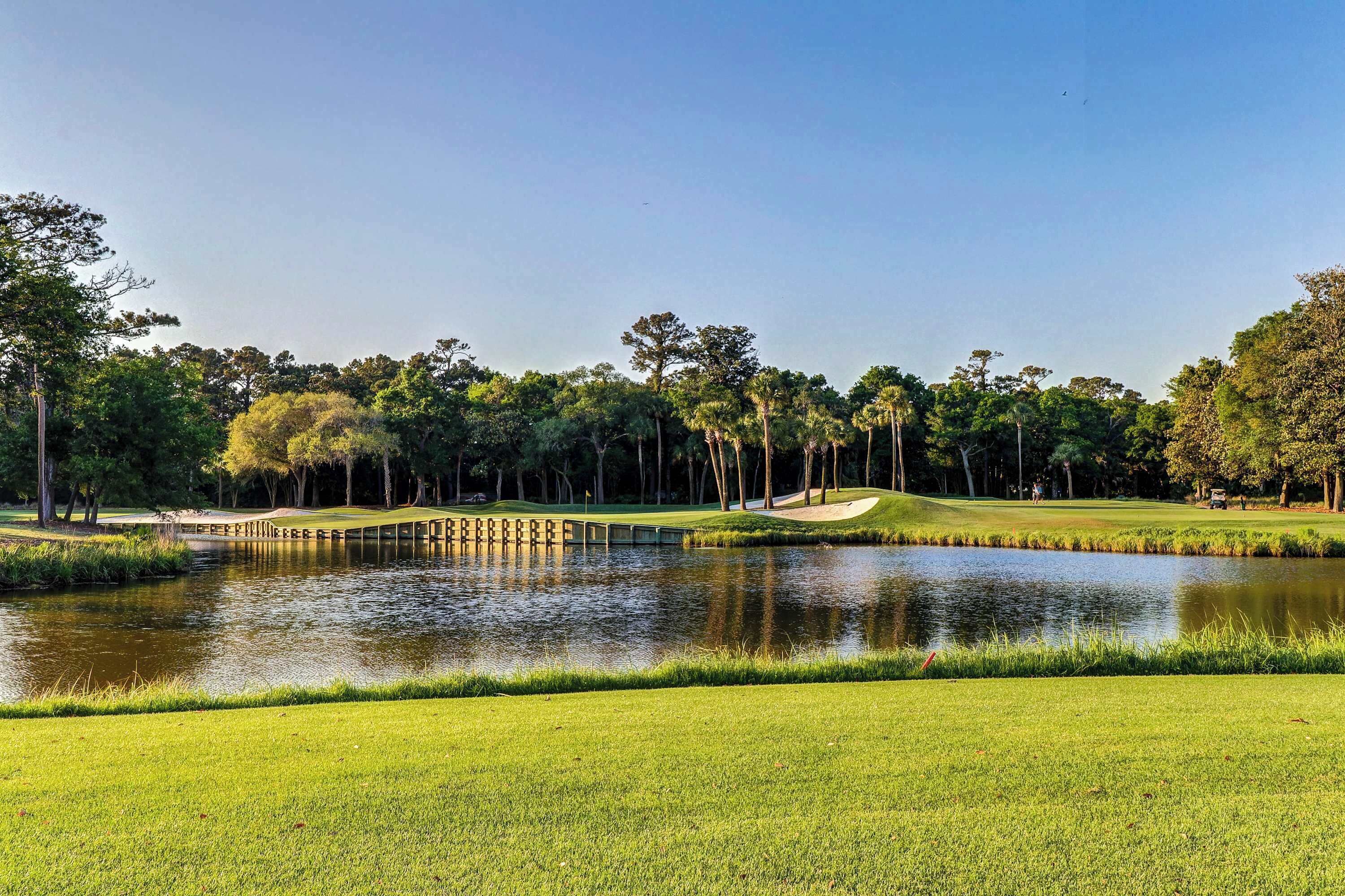 A golf course with a pond, sand bunkers, and a bridge.