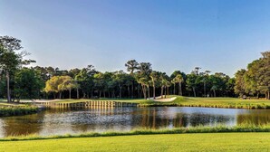 A golf course with a pond, sand bunkers, and a bridge.