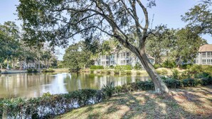 A serene lakeside setting with mature trees and a well-maintained grassy area.