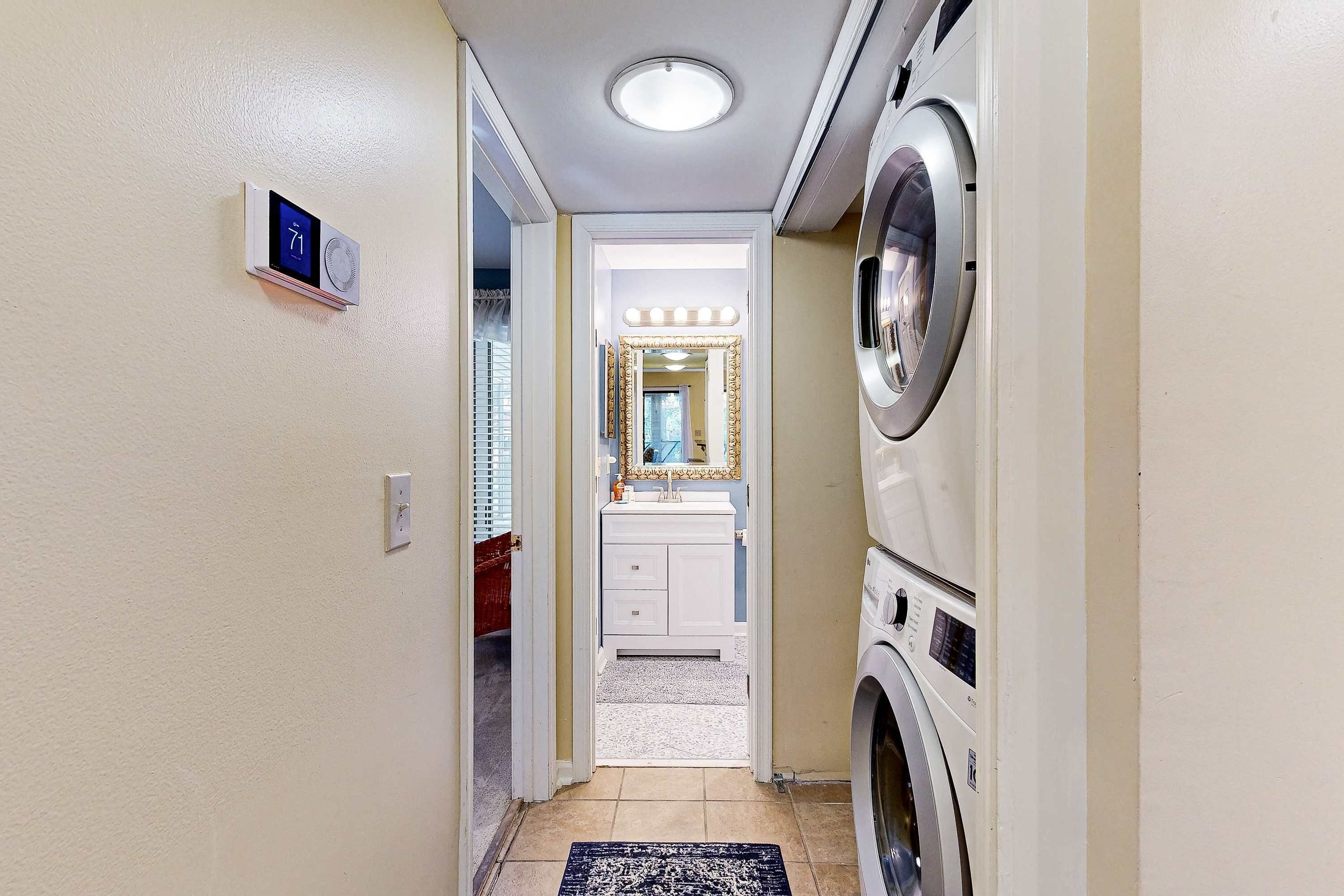 A laundry room with a washing machine, dryer, and a vanity with a mirror.