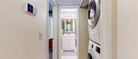 A laundry room with a washing machine, dryer, and a vanity with a mirror.