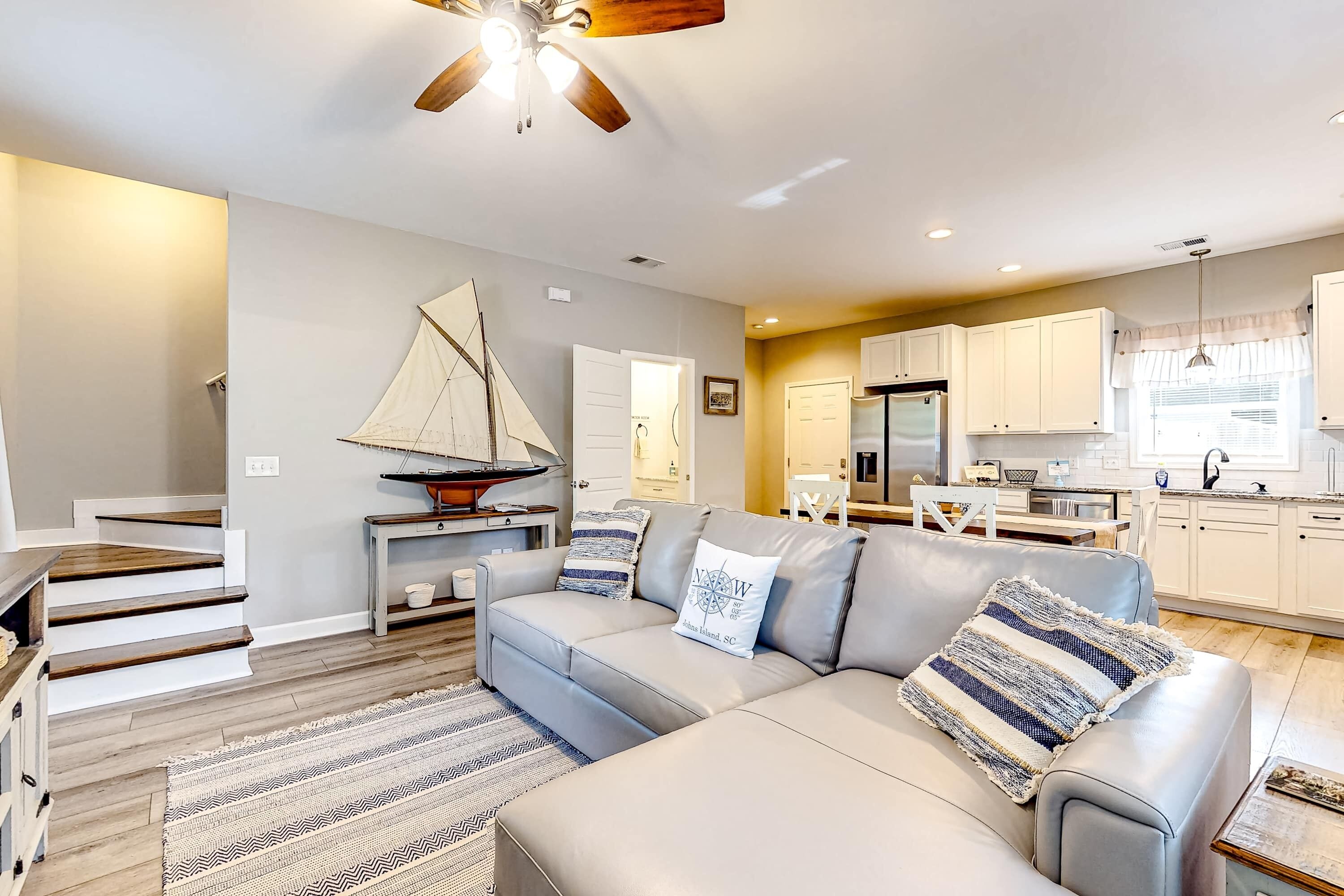 A modern living room with a grey sofa, wooden staircase, and a sailboat decoration.