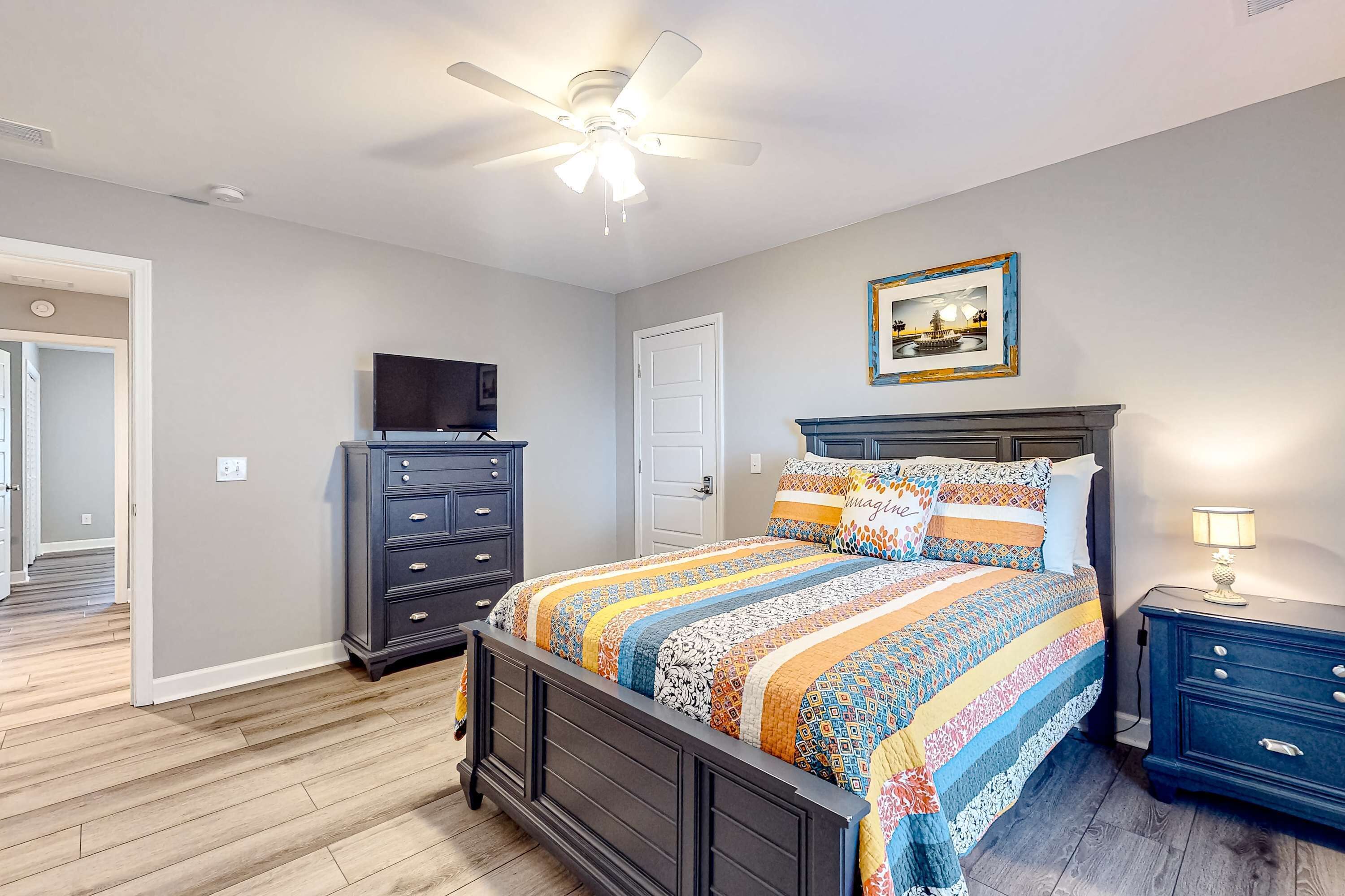 A bedroom with a bed, dresser, nightstand, and ceiling fan.