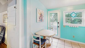 A hallway with a dining area featuring a table and chairs, a door with a window, and a ceiling light fixture.