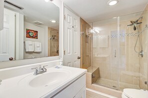 A bathroom with a white sink, a large mirror, and a glass-enclosed shower area. - Centrally located to local attractions, close to beach access & marsh views (Isle of Palms)