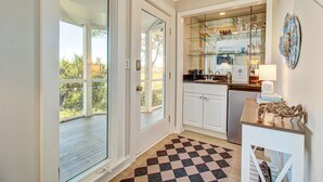 Une cuisine avec des meubles blancs, un plan de travail en bois et une étagère vitrée.