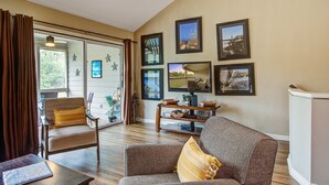 A living room with a sofa, armchair, and a coffee table. There are framed pictures on the wall and a sliding glass door leading to a patio. - Dog friendly villa (Seabrook Island)
