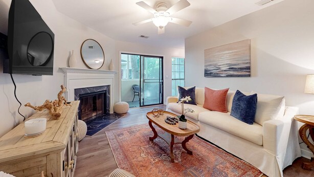 A modern living room with a fireplace, a ceiling fan, a large window, and a painting on the wall. - Stylish dog friendly, ground-floor getaway with pool, washer/dryer, & AC (Mt. Pleasant)