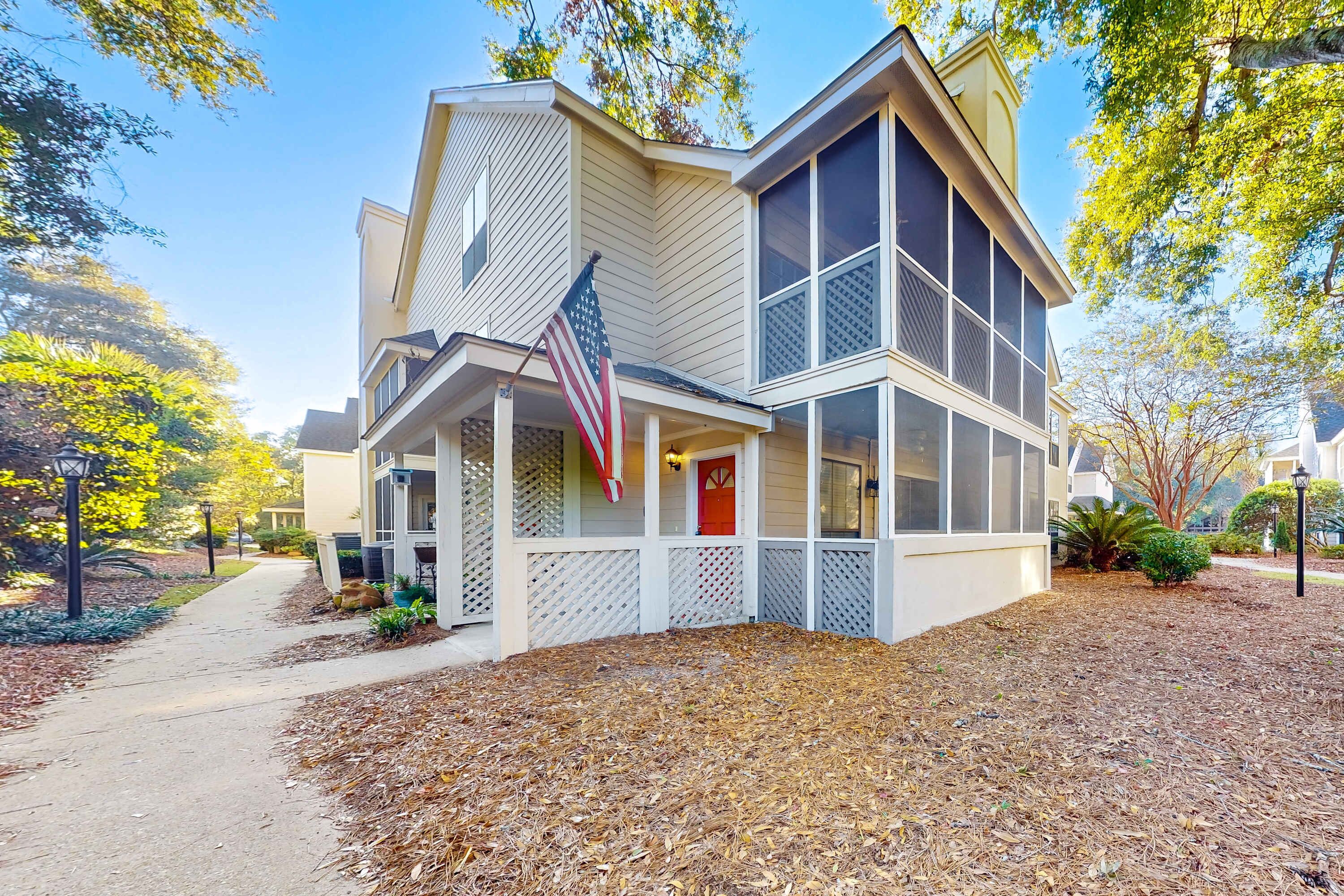 Ein zweistöckiges Haus mit Veranda, einer amerikanischen Flagge und einer roten Tür.