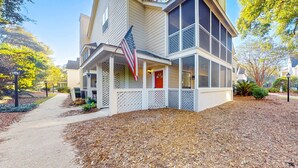 A two-story house with a front porch, an American flag, and a red door. - Stylish dog friendly, ground-floor getaway with pool, washer/dryer, & AC (Mt. Pleasant)