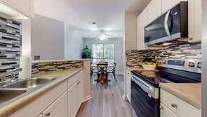 A modern kitchen with a central island, stainless steel appliances, and a dining area with a view to the outdoors. - Stylish dog friendly, ground-floor getaway with pool, washer/dryer, & AC (Mt. Pleasant)