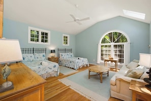 A room with two beds, a sofa, a table, and a ceiling fan.