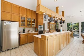 A kitchen with wooden cabinets, a stainless steel refrigerator, and hanging pots.