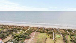 An aerial view of a coastal golf course with a beach in the background.