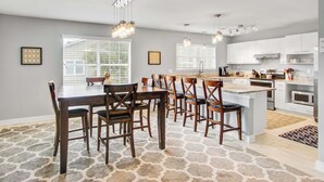 A modern kitchen with white cabinets, a central island, and pendant lighting.