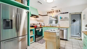 A modern kitchen with a stainless steel refrigerator, a stove, and a sink. There is a sign that reads "SWEET TEA" on the wall. - Darling, renovated home w/ beautiful backyard, W/D & WiFi - near beaches (Mt. Pleasant)
