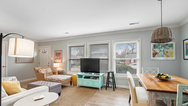 A living room with a television, a dining table, and a sofa. - Darling, renovated home w/ beautiful backyard, W/D & WiFi - near beaches (Mt. Pleasant)