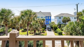 A residential street with houses, palm trees, and a clear sky. - Relaxing oceanside home w/ multiple decks, outdoor shower- steps to beach access (Folly Beach)