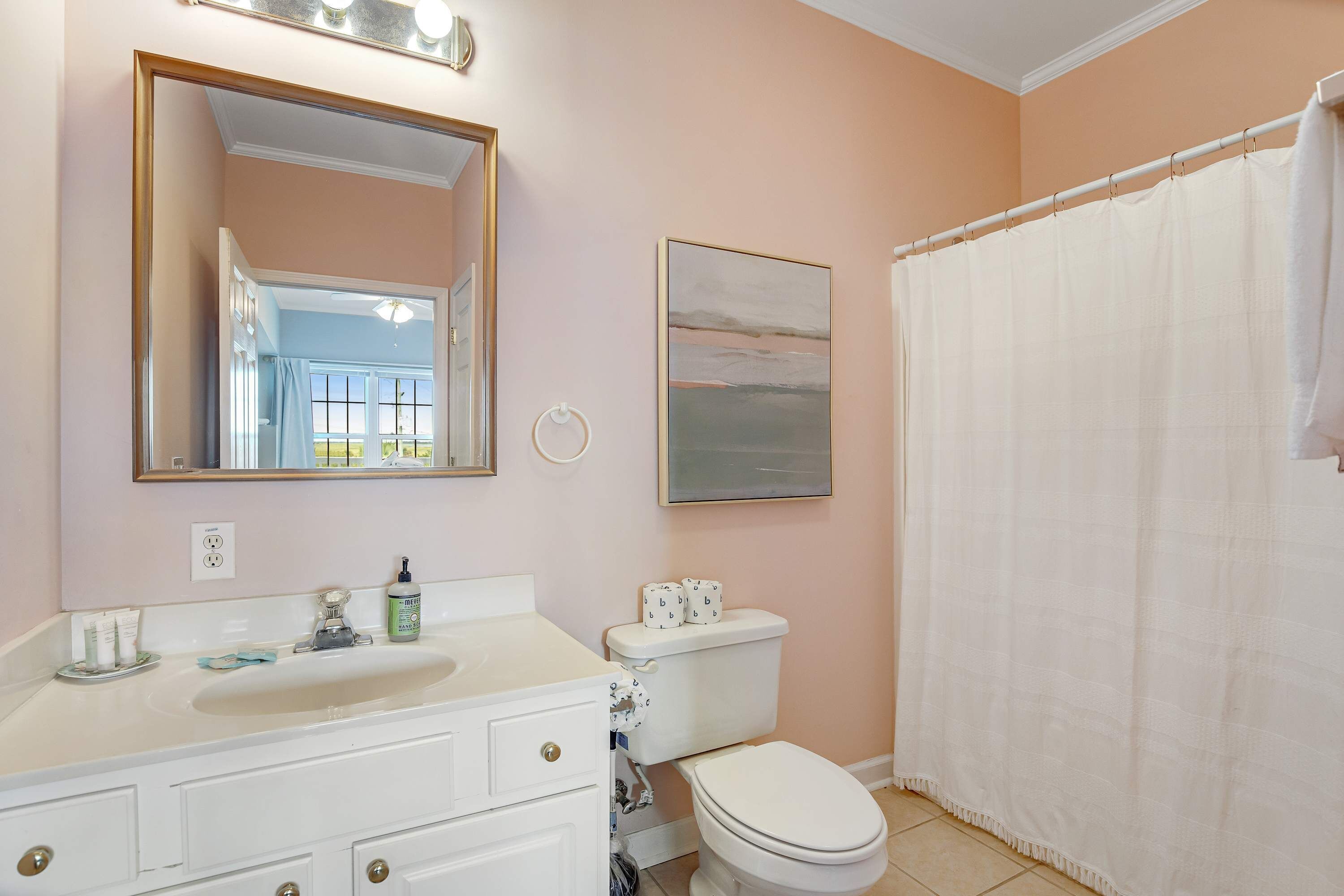 A bathroom with a white sink, mirror, toilet, and shower curtain.