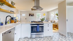 Una cocina moderna con armarios blancos, una campana de acero inoxidable y un horno integrado.