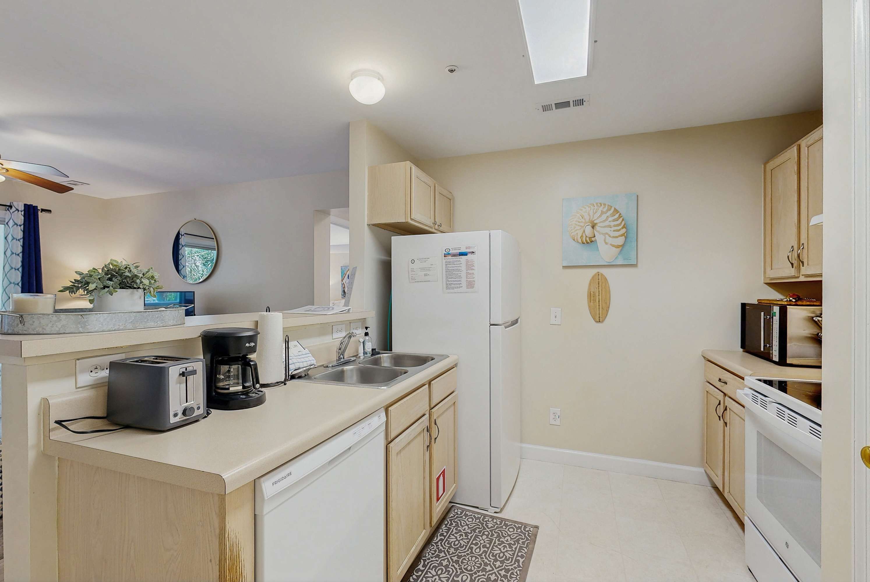 A compact kitchen with a toaster, coffee maker, refrigerator, and microwave.