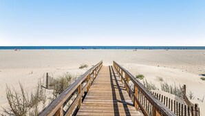 Una passerella di legno che conduce a una spiaggia sabbiosa sotto un cielo sereno.