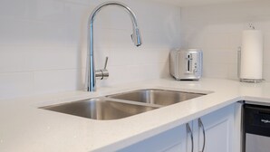 Una cocina moderna con un lavamanos de acero inoxidable, un tostador y un lavavajillas.