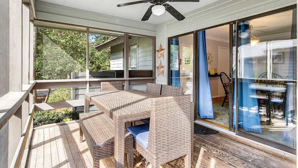 Eine überdachte Terrasse mit Korbmöbeln, einem Deckenventilator und großen Schiebegläsern zu einem Außenbereich.