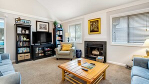 Ein Wohnzimmer mit Kamin, Fernseher, Bücherregal und einer Couch.