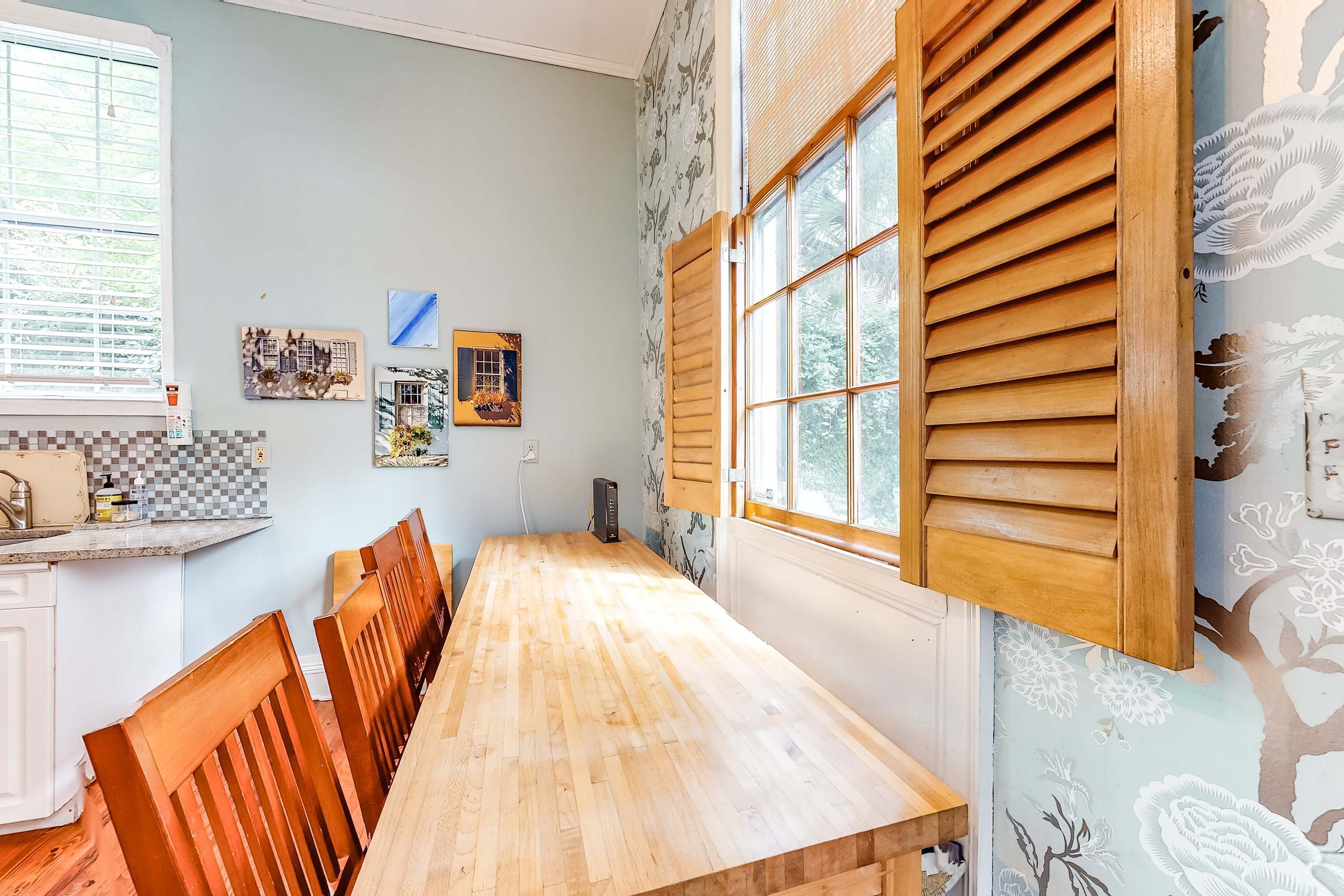 Un espace repas avec une longue table en bois, des chaises et une fenêtre dotée de volets en bois.